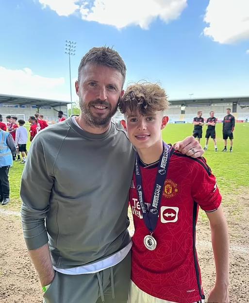 Michael Carrick and son Jacey with medals on a football field.