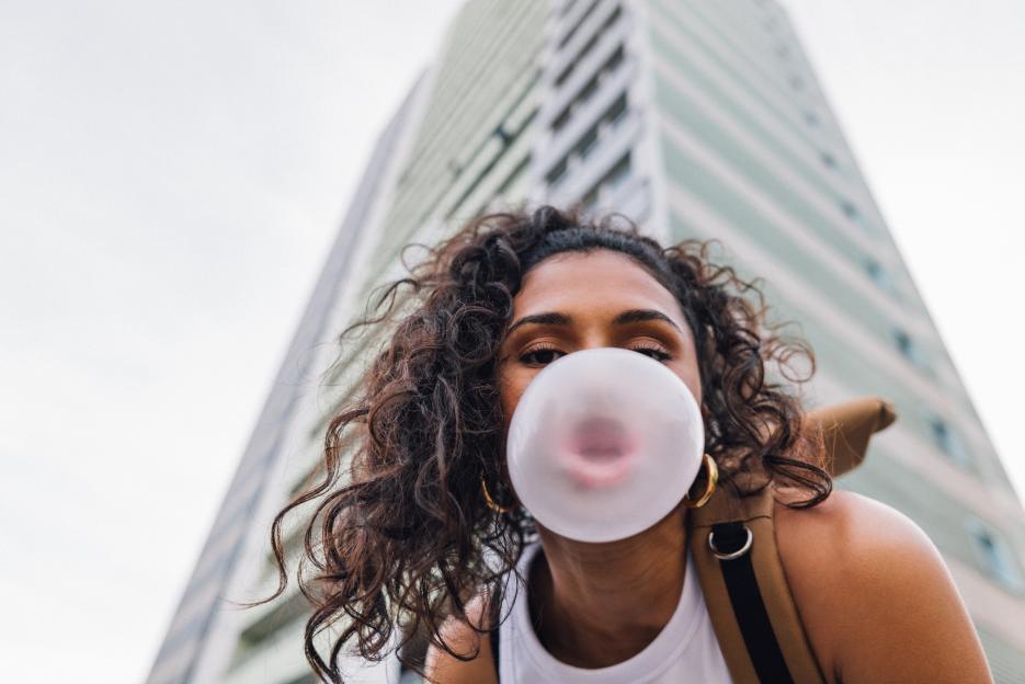 Woman blowing bubble gum bubble in front of residential building