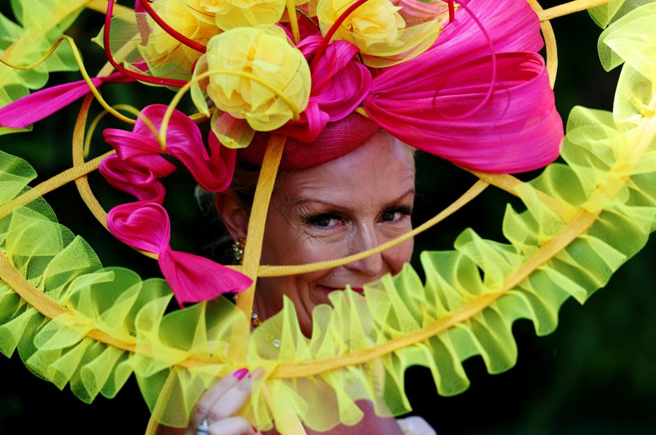 A woman partially obscured by a large, elaborate hat with pink and yellow fabric.