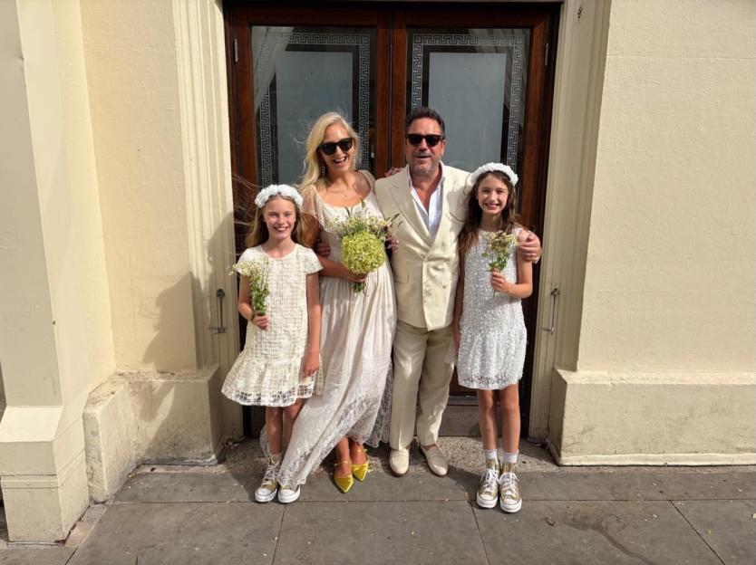 Rufus Jones and Philippa Allam with two flower girls, celebrating their marriage.