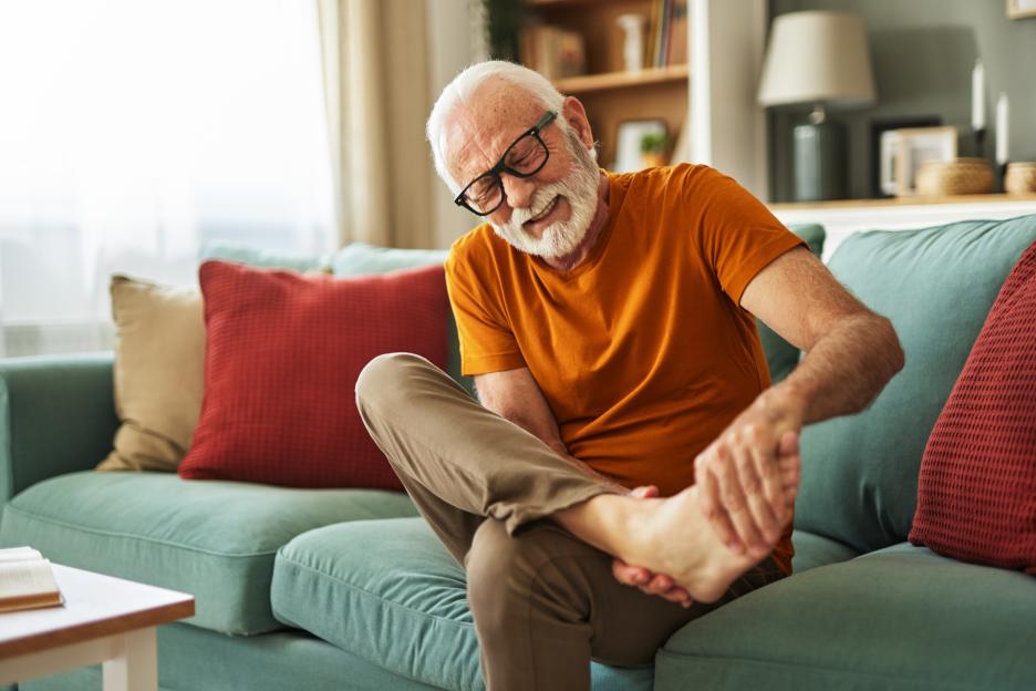 Senior man holding his ankle due to painful joint ache.