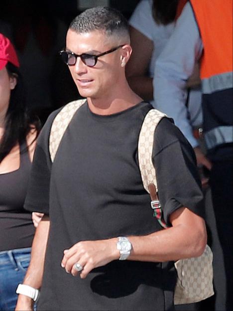 Cristiano Ronaldo wears a black t-shirt, sunglasses, watch, and Gucci backpack, with a ring on his finger.