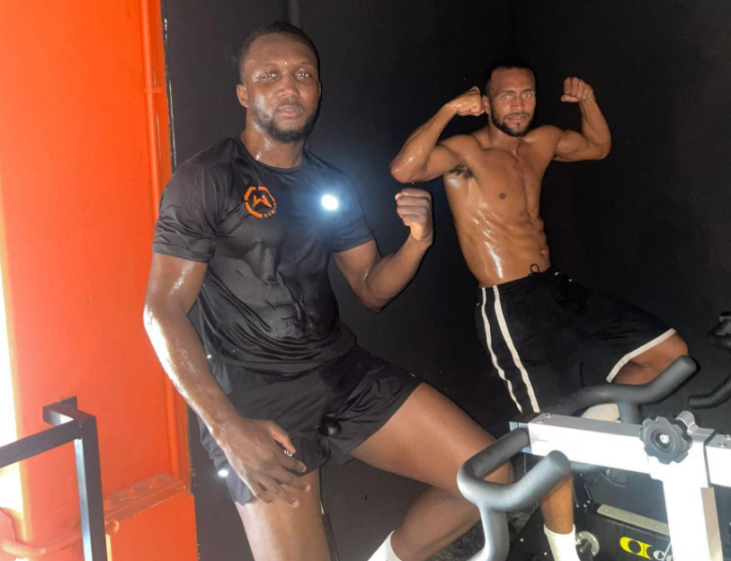 Two men on exercise bikes in a gym.