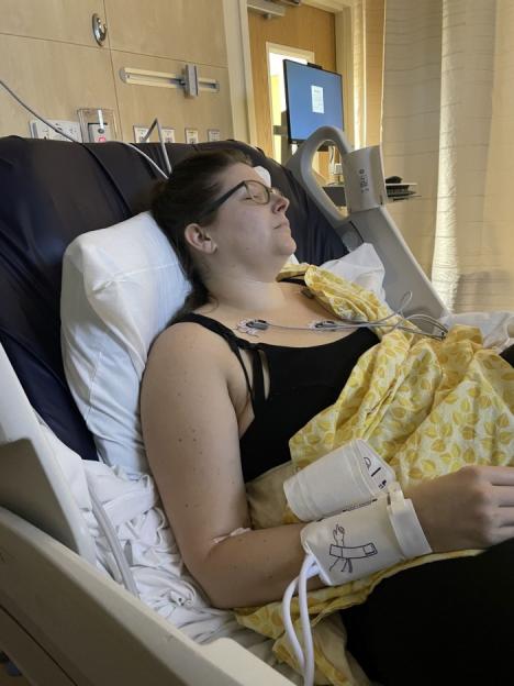 A woman lying in a hospital bed with medical monitoring equipment attached to her.