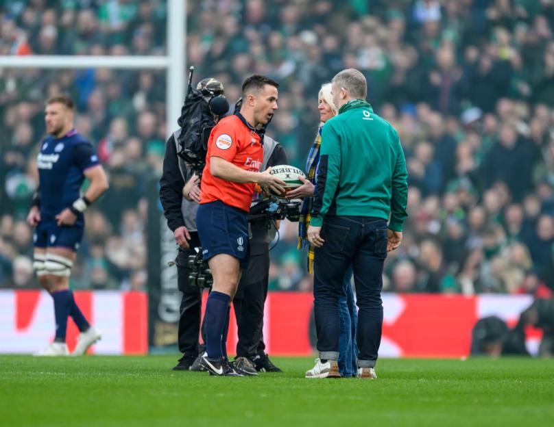 Referee Luke Pearce holds a rugby match ball speaks to Kathy Weir and Gordon D'Arcy on the field