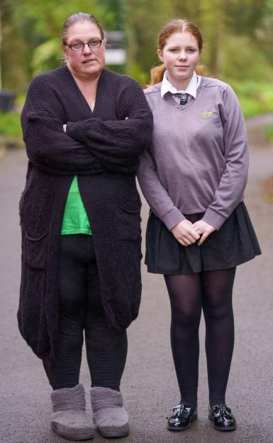 Sarah Fielmar, mother of Phoebe Simmons, stands with Phoebe, who is wearing a school uniform, to protest the school's ban on jumpers.