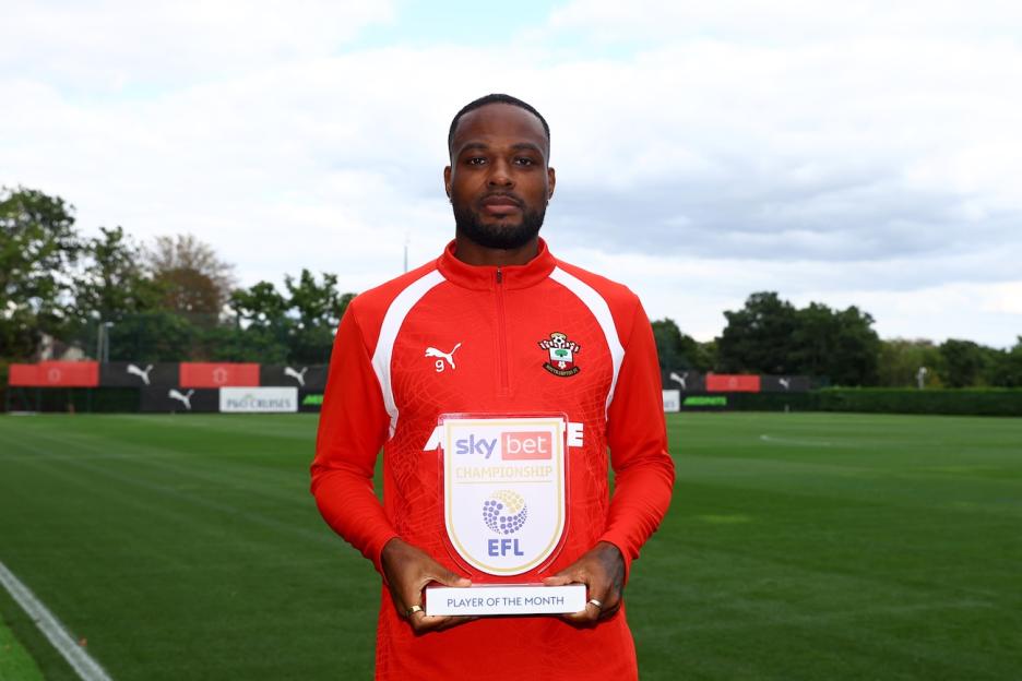 A man in a red and white sports top holding the Sky Bet Championship Player of the Month award.