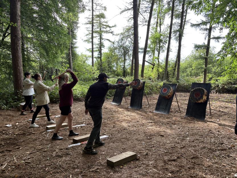 Four adults axe throwing at Camp Wildfire in the UK.