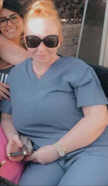 Debbie Brannan, a woman who opened up about her weight loss journey, in a blue scrubs-like top and pants, and sunglasses, holding a phone.