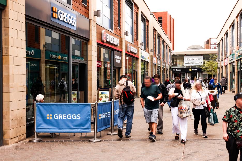 People walking past Greggs and Burger King stores with "Gateshead Interchange" visible in the background.