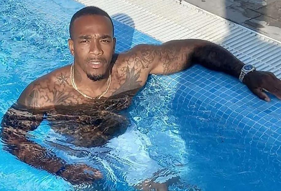 Man with tattoos and a watch lounging in a swimming pool.