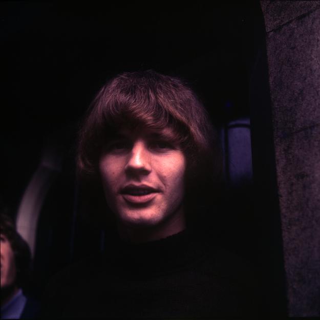 Portrait of a young man with shaggy brown hair and an open mouth.