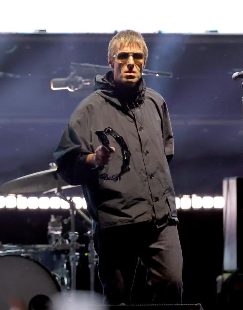 Liam Gallagher performs onstage at the Rose Bowl, holding a tambourine.