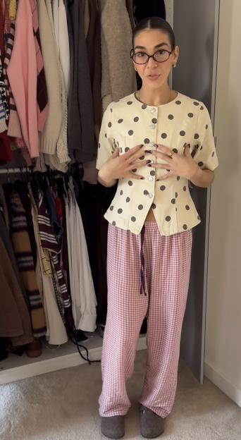 Woman wearing a polka dot top, checkered trousers, and slippers.