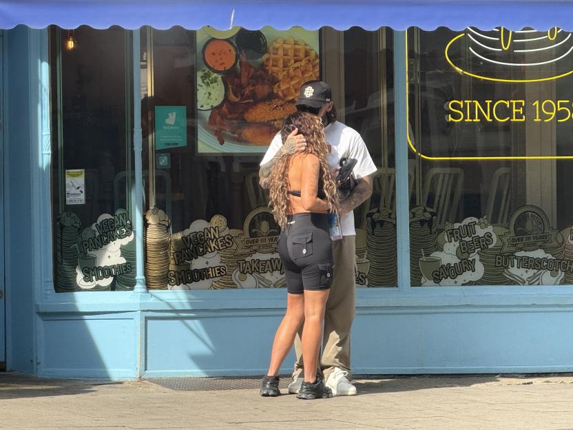 Jesy Nelson and Ben Davies embracing in front of a pancake house window.