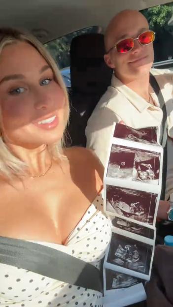 A couple in a car holding up several ultrasound images.
