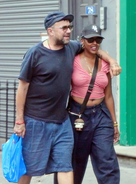 Damon Albarn and Rebecca Freckleton smiling and holding hands while walking in London.