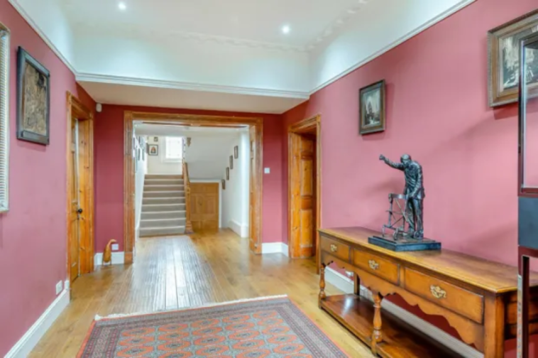 Hallway with wooden floors, a staircase, and a wooden console table with a statue.