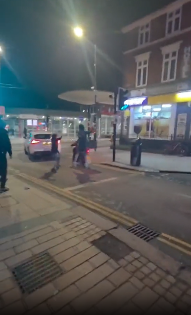 People fleeing from a car at night in a city.