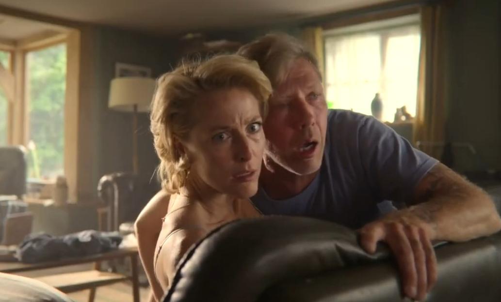 Gillian Anderson and a man looking distressed behind a couch.
