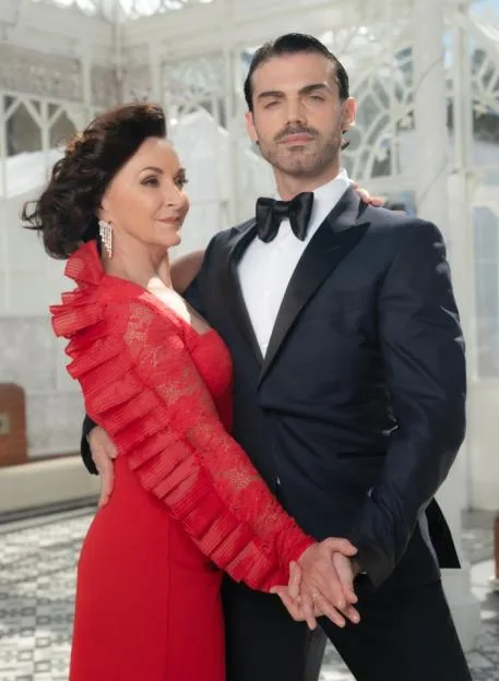 Shirley Ballas in a red dress posing with dance student Giuseppe Nonnis in a tuxedo.