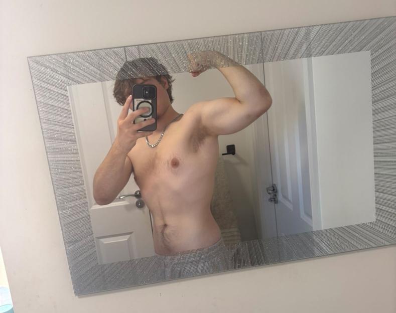 Tommo Holbrook flexing his bicep in a mirror.