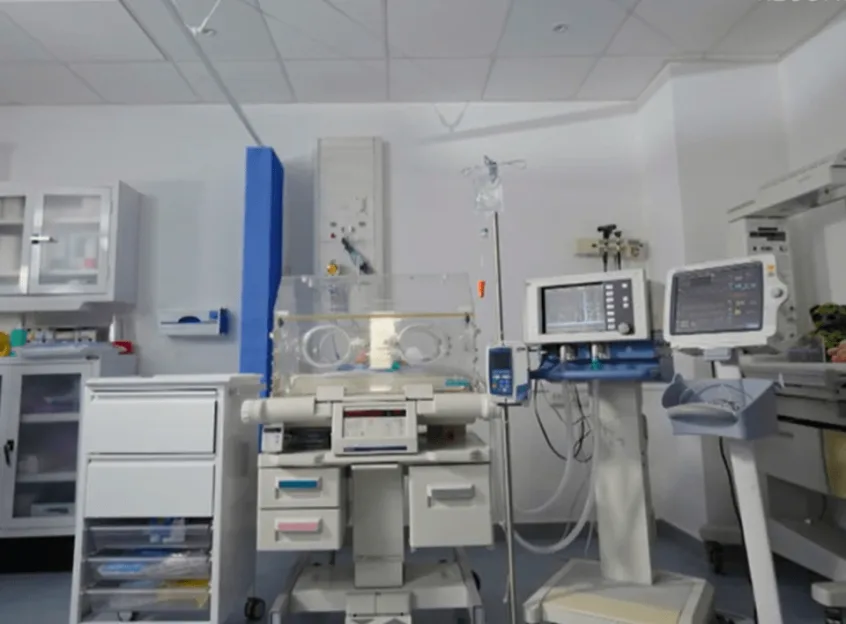 A medical room with an infant incubator and monitoring equipment.
