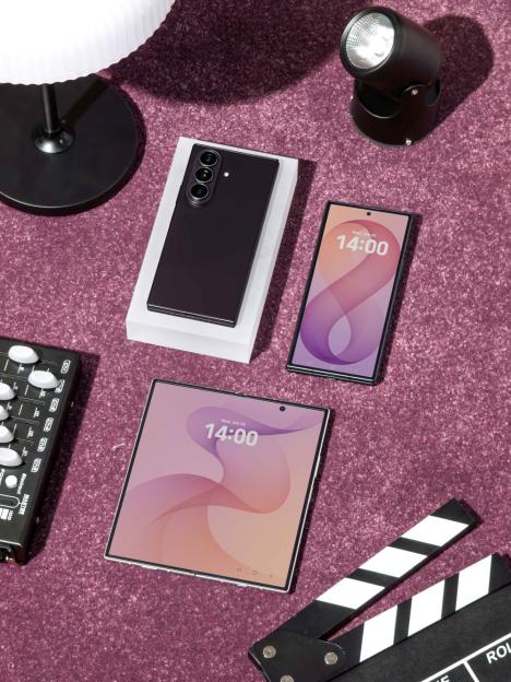 Three Samsung Galaxy Z Fold5 phones on a purple surface next to a clapperboard.