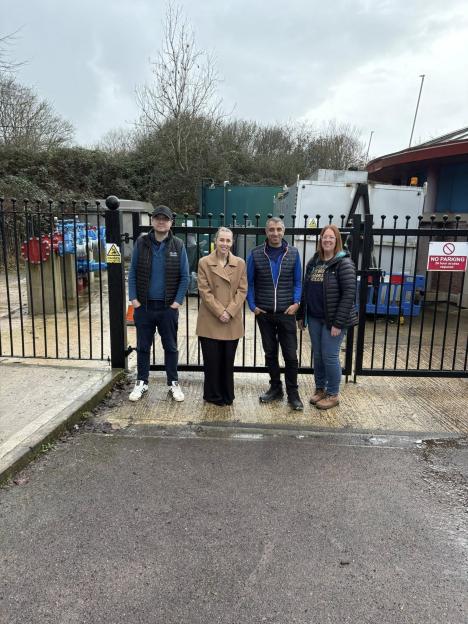 Four people standing in front of a fenced-off pumping station, including Haydon Wick Parish Councillor Vinay Manro (second from right).