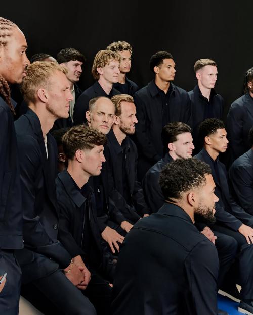 A group of men in dark clothing pose for a photoshoot.