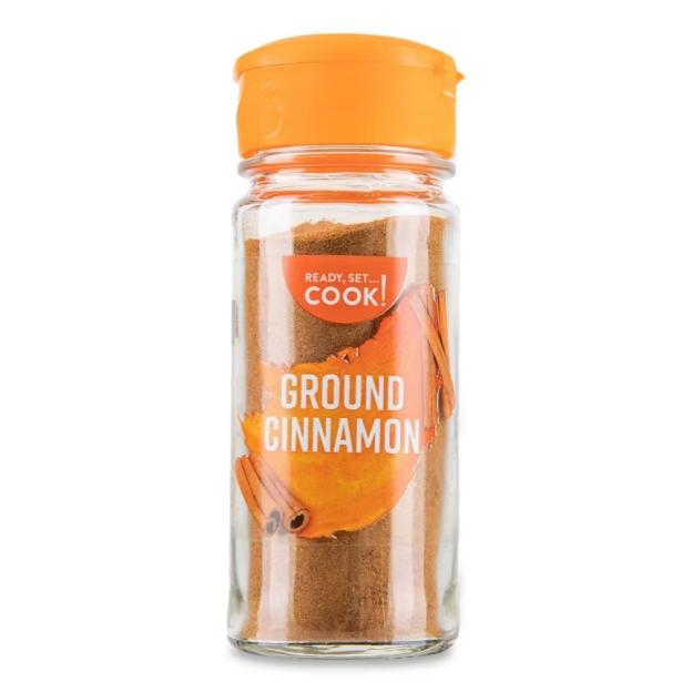 A jar of ground cinnamon with an orange cap.