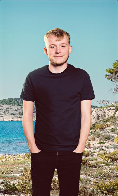 Man in a black shirt and jeans standing in front of an island landscape.