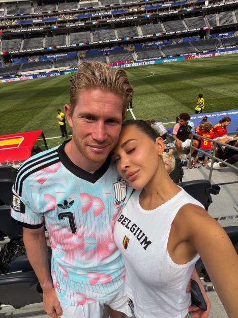 Michèle De Bruyne and Kevin De Bruyne take a selfie at a soccer stadium.
