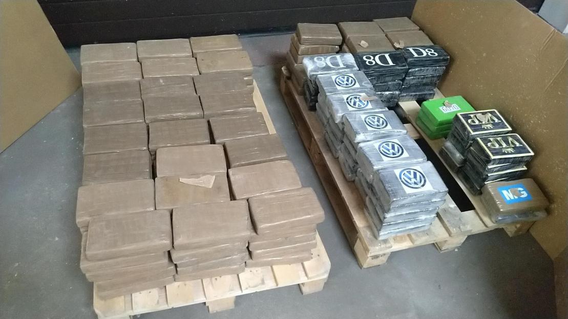 Bundles of drugs, some marked with a Volkswagen logo and other labels, on pallets.