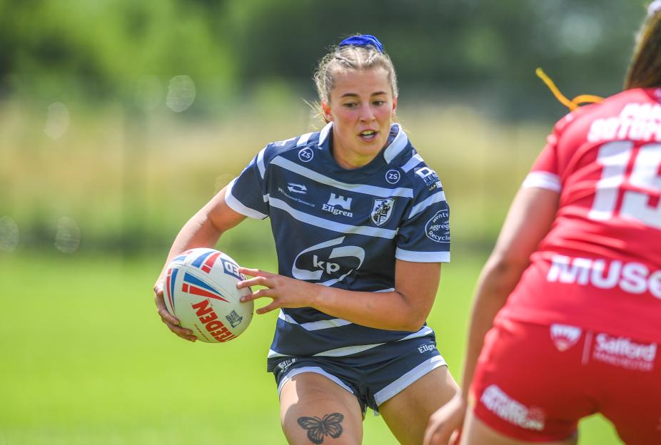 Charley of Featherstone Rovers' women's side in a navy and white striped uniform holding a rugby ball during a match.