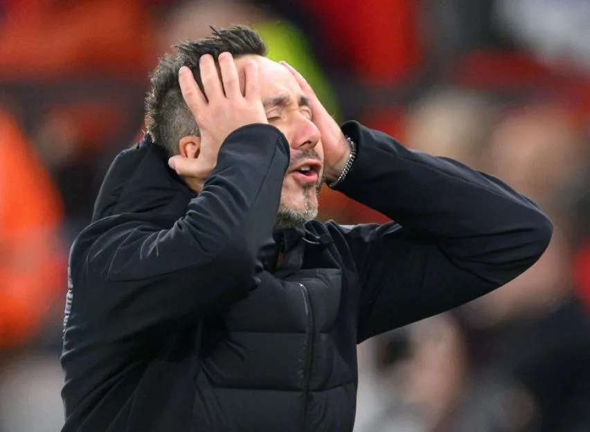 Tottenham manager Roberto De Zerbi holding his head in his hands in dismay on the touchline.