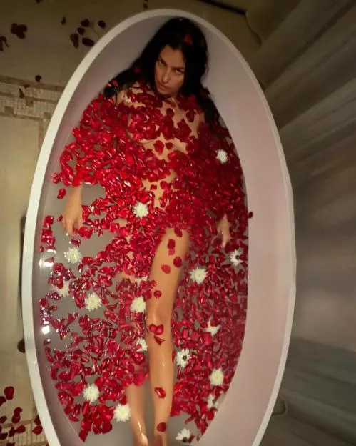 Irina Shayk lies in a bathtub filled with water and red rose petals.