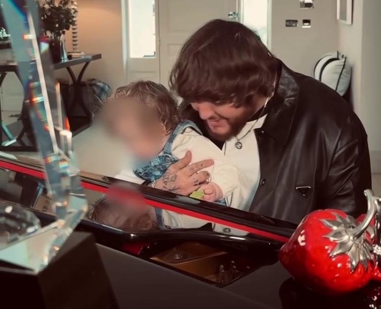James Arthur holding his daughter Emily at a piano.