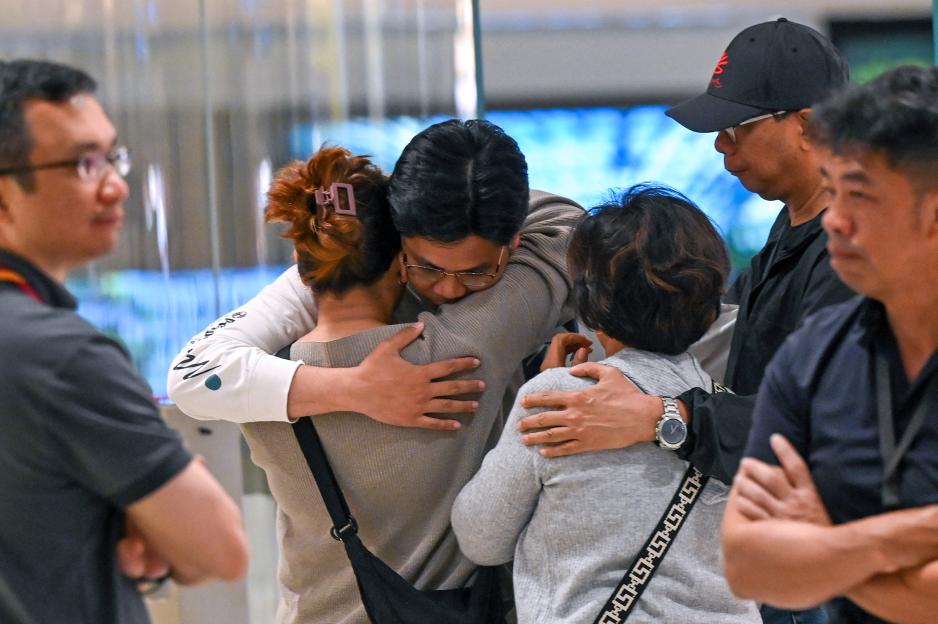 Passengers from Singapore Airlines flight SQ321 embrace family members upon arrival at Changi Airport.