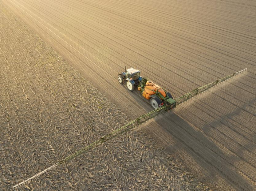 Agricultural sprayer in a field, seen from above.