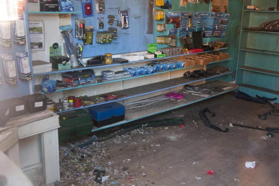 Interior of an abandoned pet shop with shelves of dusty merchandise and debris on the floor, once home to an infestation of rats.