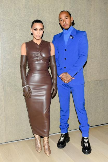 Kim Kardashian in a brown leather dress and Lewis Hamilton in a blue suit.