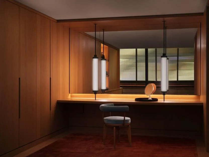 A green room with wood paneled walls and vanity, two hanging pendant lights, and a blue chair.