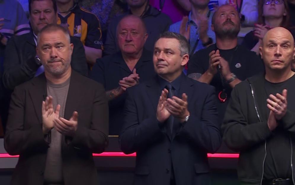 Audience members clapping in a crowded room.