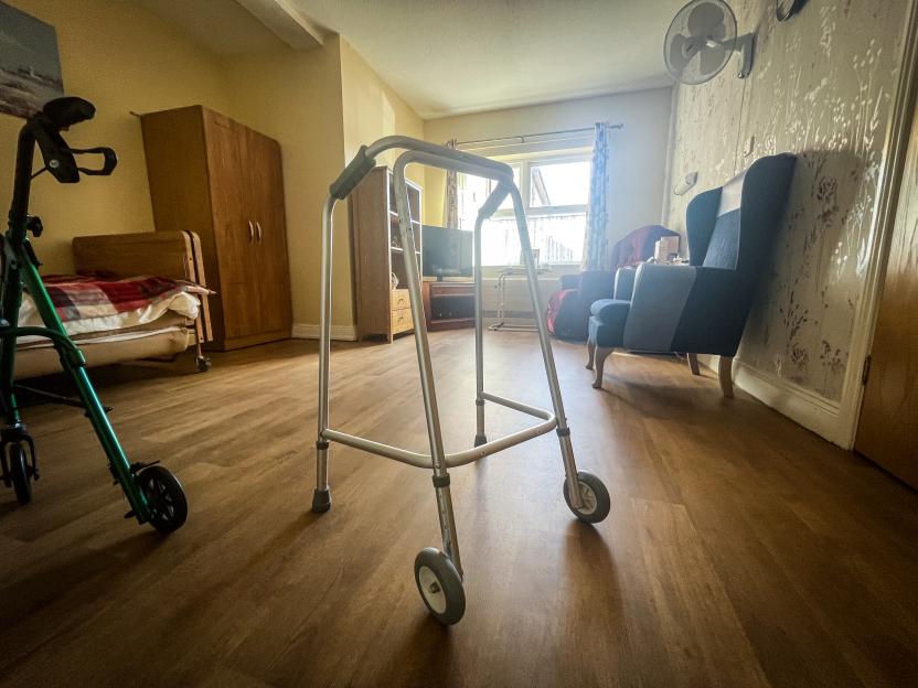 A walker and a mobility aid in a residential care home room.