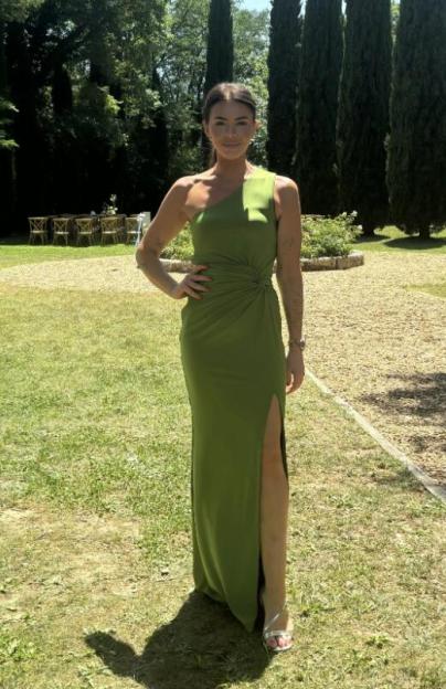 Amy Salmon in a green one-shoulder dress, standing outdoors.