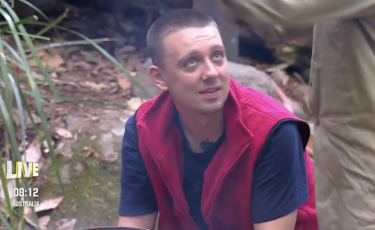 A man in a red vest and blue shirt looks up.
