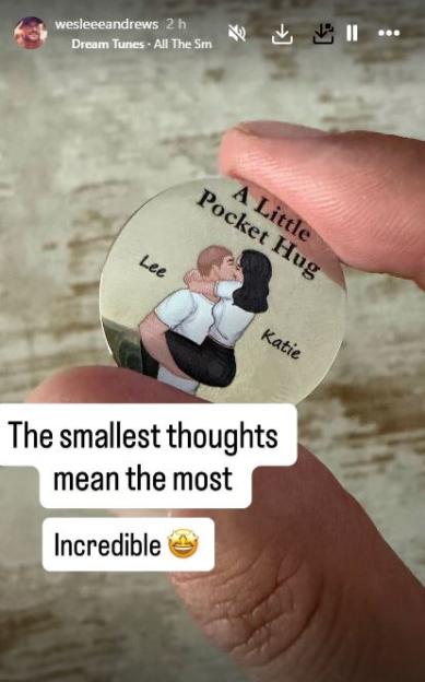 A man's hand holds a coin with an illustration of a couple embracing, labeled "A Little Pocket Hug," "Lee" and "Katie."