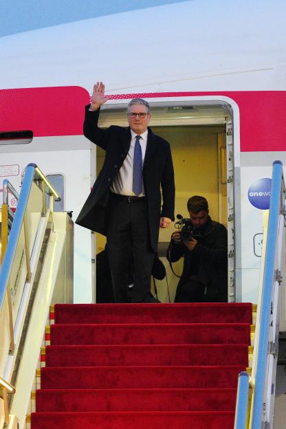 Britain's Prime Minister Keir Starmer waves upon arrival at an airport.