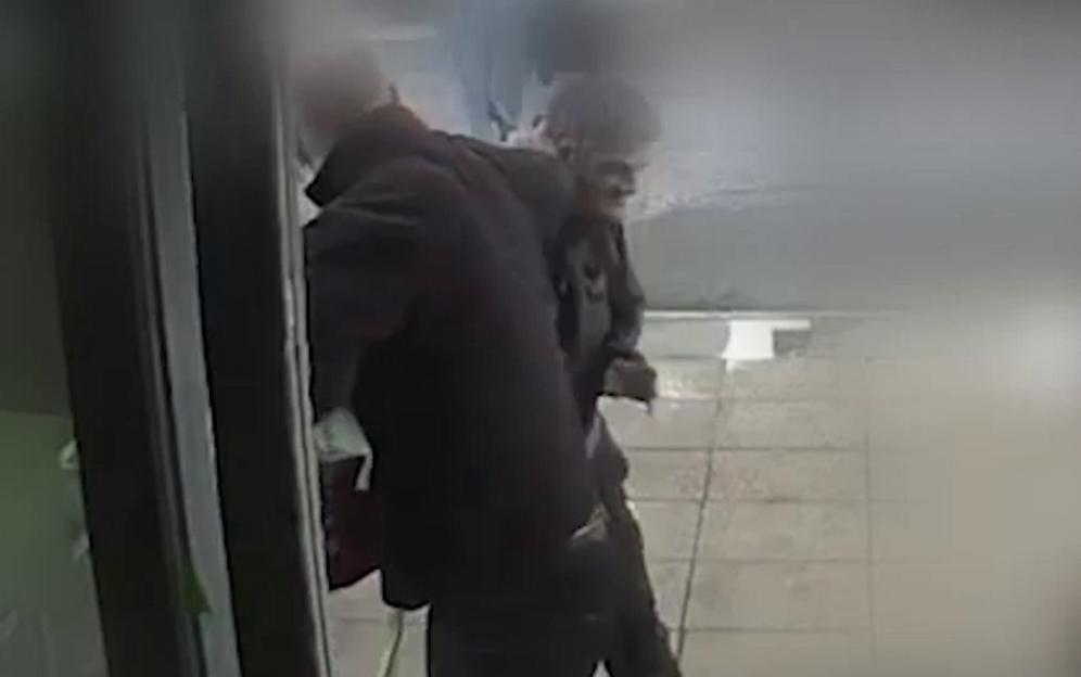 Nicholas Noble being restrained by a member of staff.